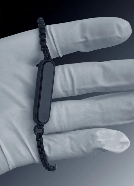 Sleek black chain bracelet with rectangular plate held by gloved hand, Éclat modern accessory