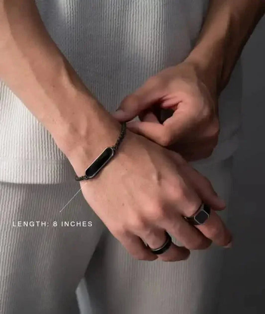 Man wearing a black chain bracelet and rings, showcasing premium modern jewelry by Éclat.